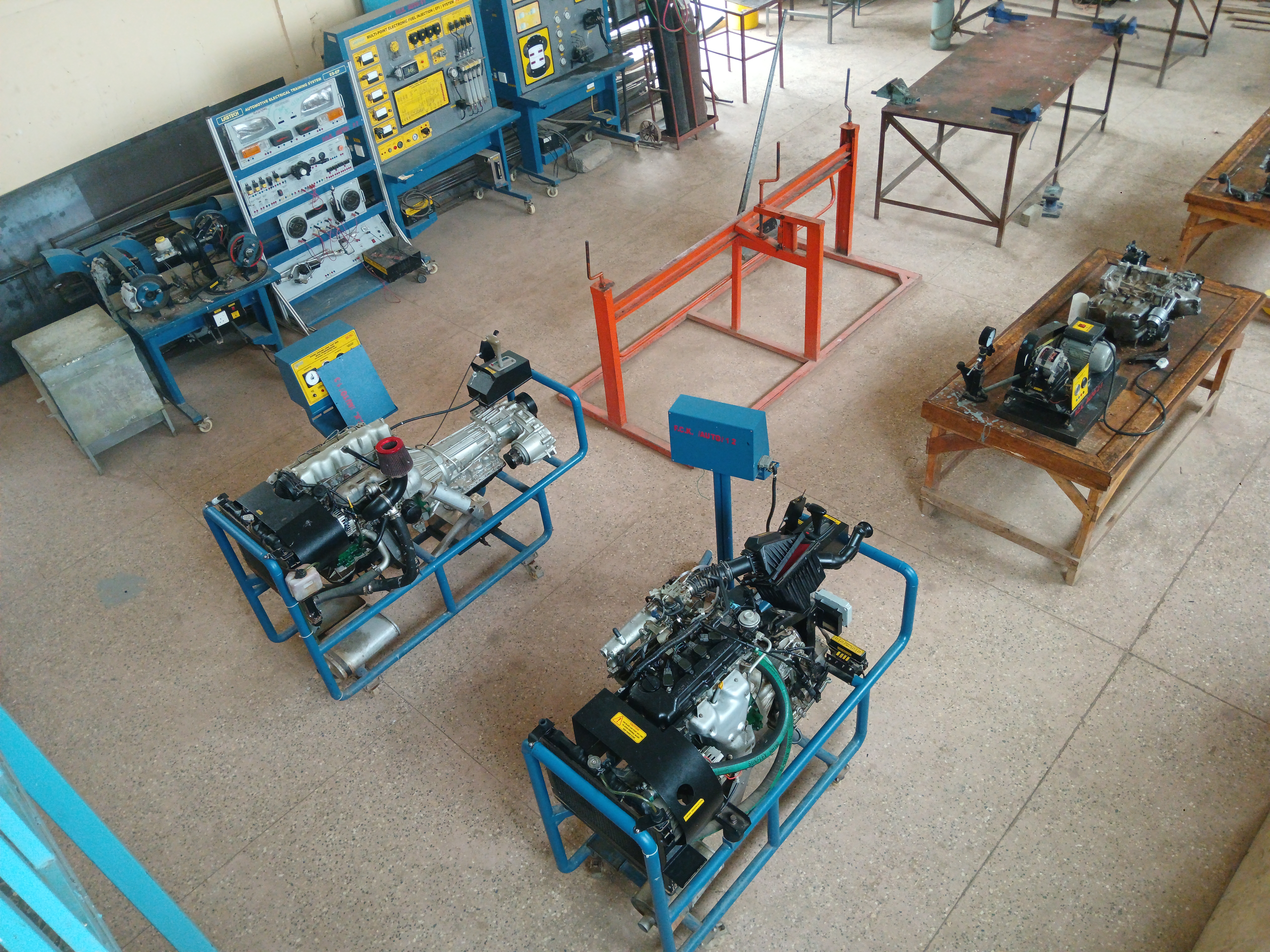 This image shows a large automotive training workshop, viewed from above at a slight angle.